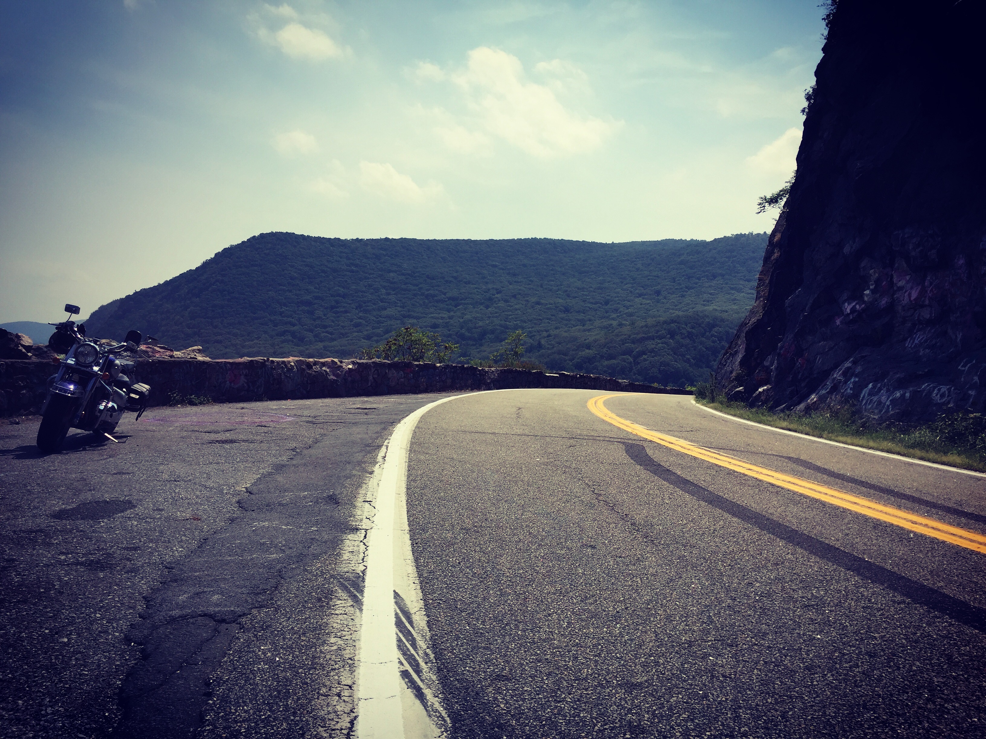 Motorcycle parked on the side of a curvy windy road at Storm King Mountain.